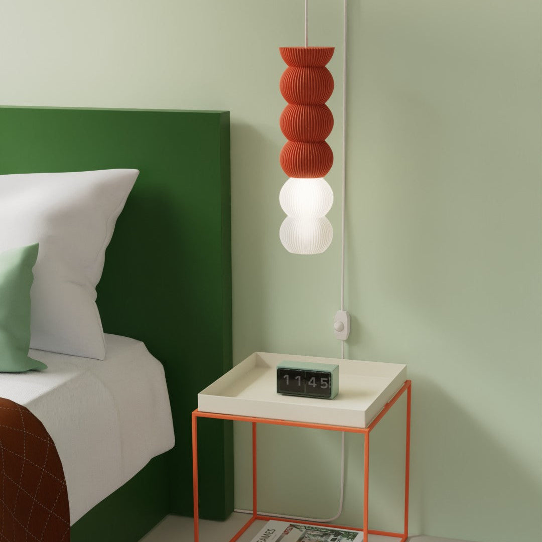 Modern bedroom with a green headboard, white bed, and an orange hanging pendant STAK lamp above the side table.